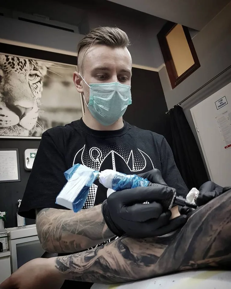Marcin Nencek przy pracy — tatuaż na nodze klienta, studio Grey Eye Tattoo w Krakowie